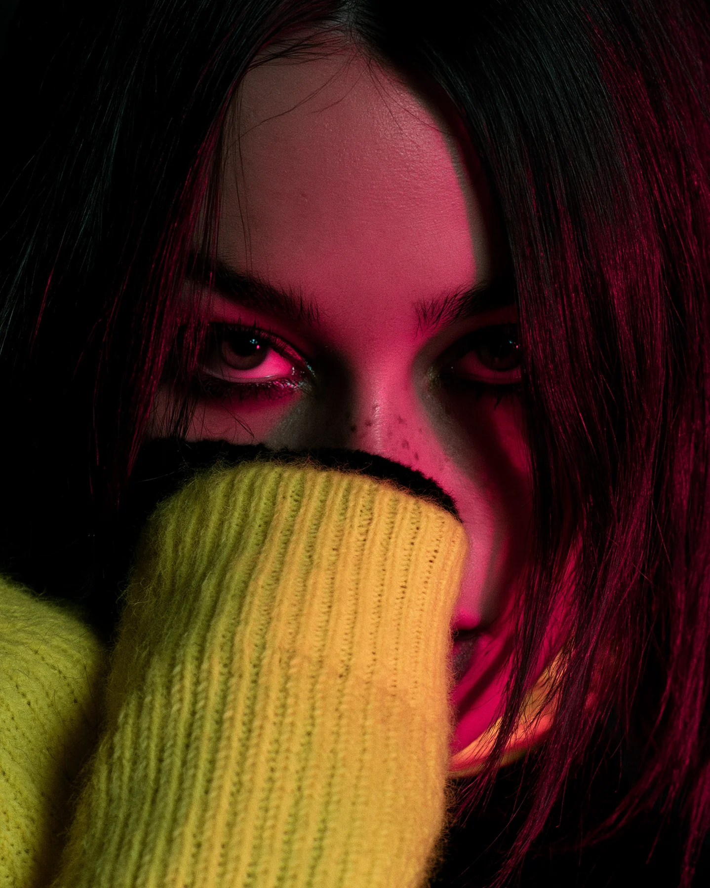 A cinematic close portrait with yellow knitwear and pink side light.